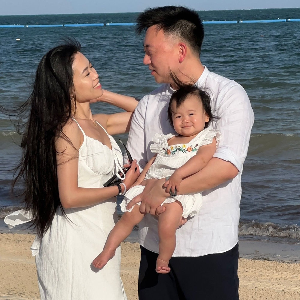 Maggie and Mike holding Ellie together on the beach